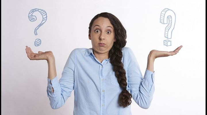 woman shrugging with question marks in hands