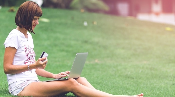 woman with credit card and laptop in grass