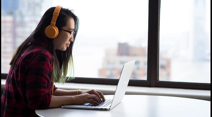 woman wearing headphones working on laptop