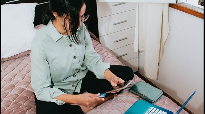 woman sitting on bed with laptop and phone