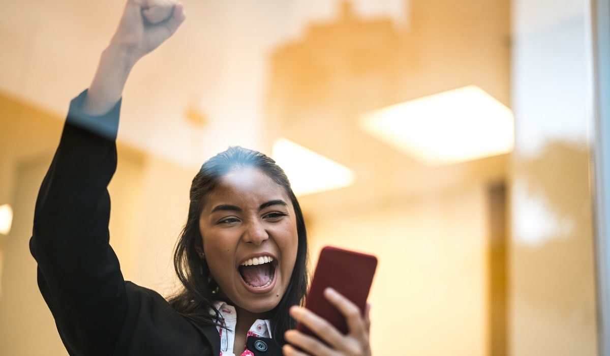 female student looking at phone and celebrating