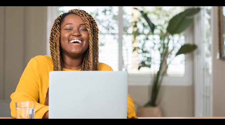 female laughing and typing on laptop