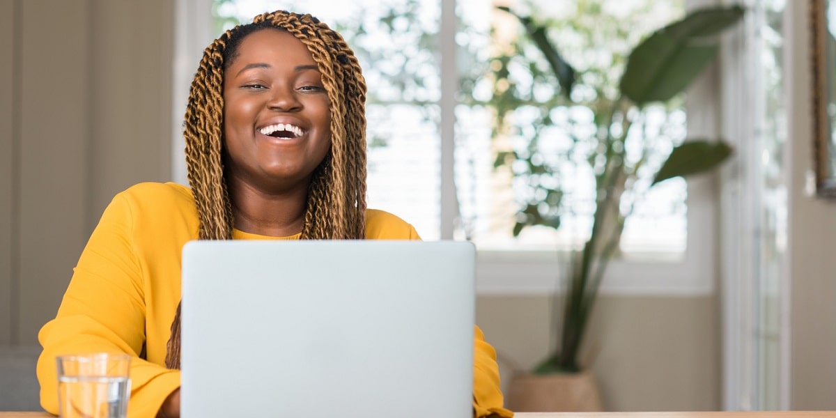 female laughing and typing on laptop