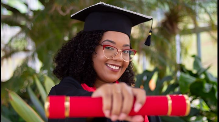 female graduate holding diploma in outstretched hand