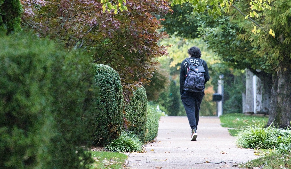 student wearing backpack walking on college campus