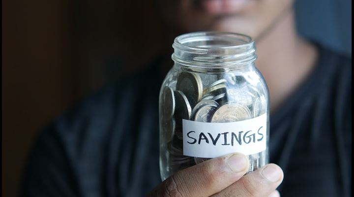 man holding jar of coins labeled savings