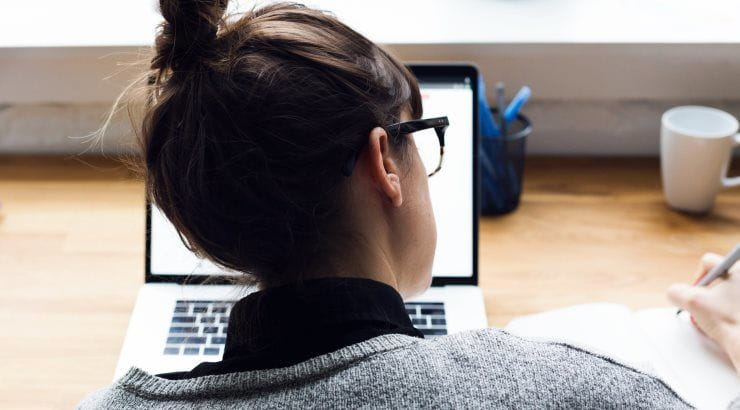 female-taking-notes-and-browsing-laptop