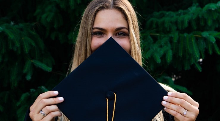 woman covering her face with grad cap