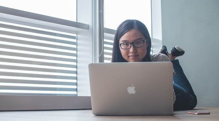 young woman lying down looking at laptop