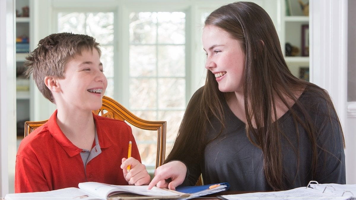 brother and sister doing homework and laughing