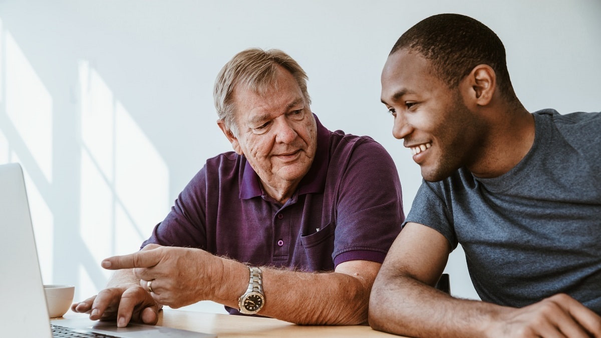 older man working with young man on computer