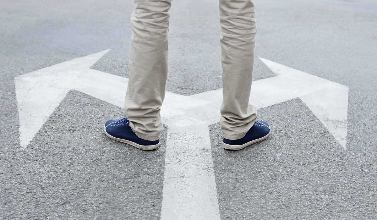person standing on arrows deciding which direction to go
