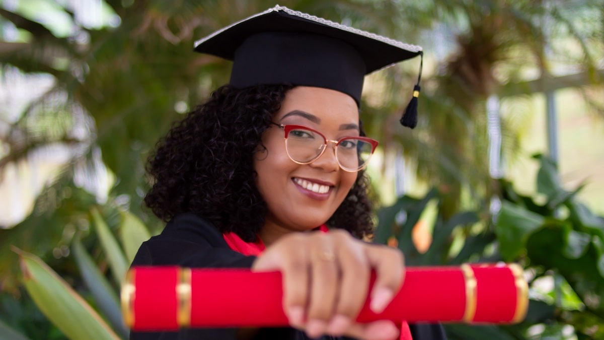 female graduate holding diploma in outstretched hand