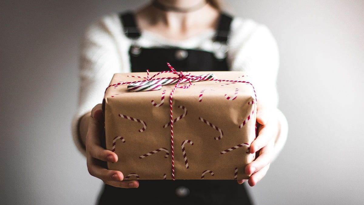 person holding a present in candy cane wrapping paper