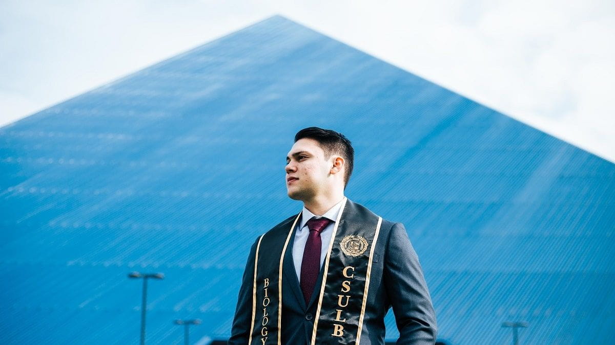 graduate in front of building at Cal State Long Beach