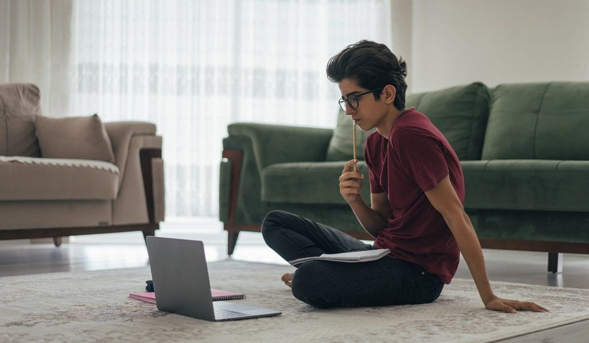 teen sitting on floor working on laptop