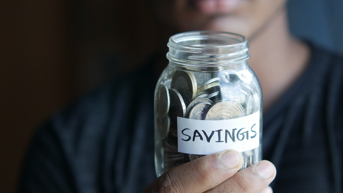 man holding jar of coins labeled savings