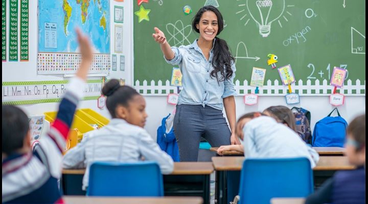 elementary school teacher smiling in classroom full of students