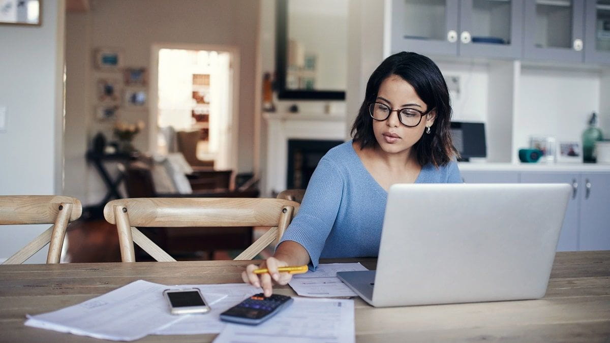 woman using calculator and laptop to pay bills