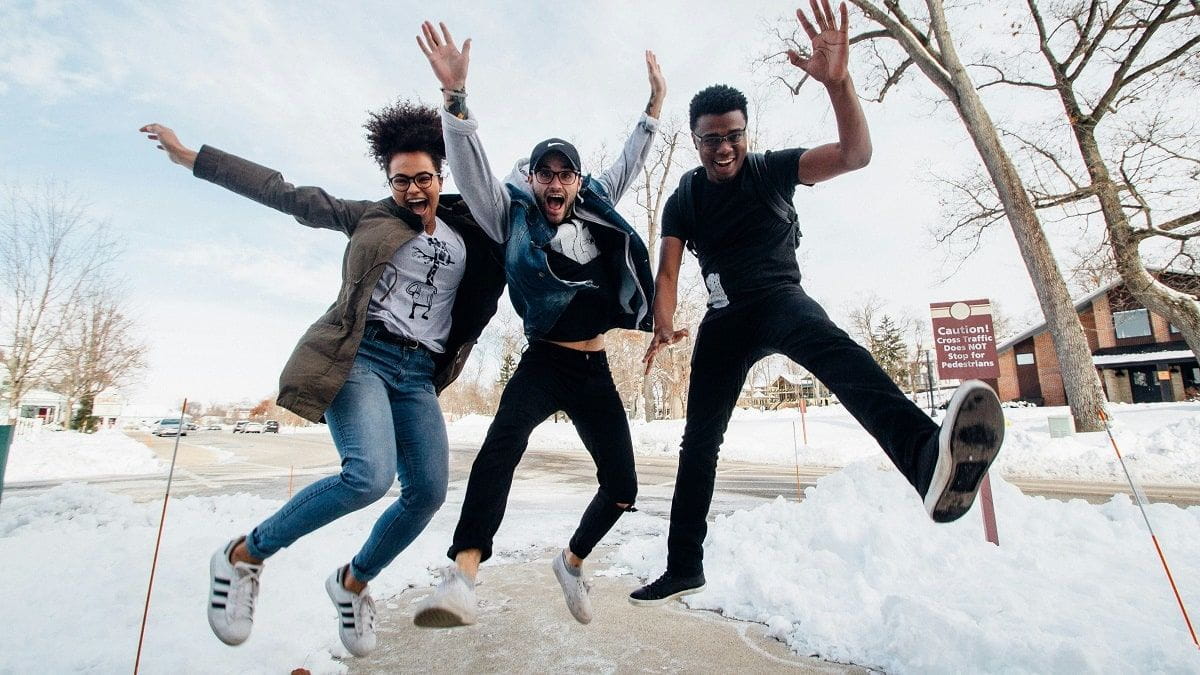 three college students jumping for joy outside in the show