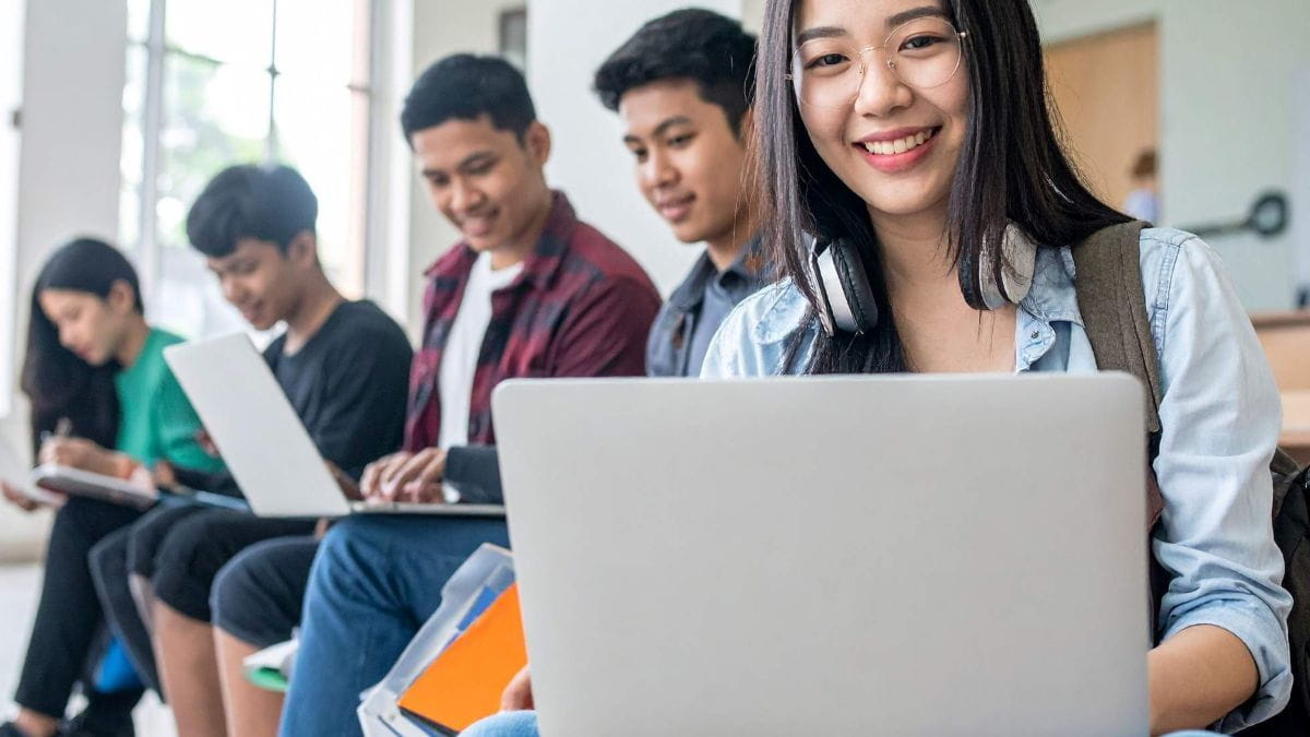 smiling students working on laptops