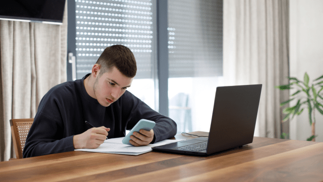 Student doing homework using a laptop and phone