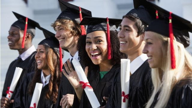 Students in graduation gowns carrying diplomas